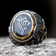Detailed view of the Turkish signet ring's black oval face with white ethnic symbol and gold-toned braided border.