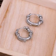 Pair of silver-toned snake huggie earrings displayed flat on a dark backdrop