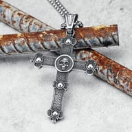 Detailed view of the stainless steel skull cross pendant resting on a fingertip