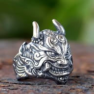 Detailed view of the Oni mask ring's forehead and eyes against a blurred green background.
