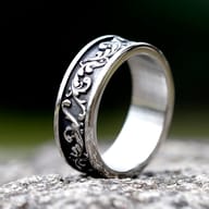 Detailed view of the dark, swirling scroll pattern on the silver stainless steel ring band.