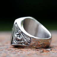 Close-up of the square ring face, showcasing the death sickle skull design and textured edges on a rustic surface.