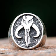 Full view of the stainless steel Mandalorian Mythosaur skull signet ring on a rustic surface.