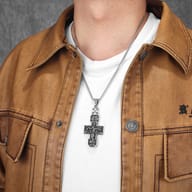 The Orthodox crucifix pendant resting on a textured surface, showcasing its weight and dimensions.