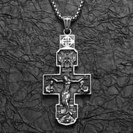 Close-up of the left side and lower part of the Orthodox crucifix pendant, emphasizing carved figures.