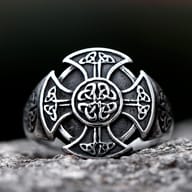 Front close-up view of the stainless steel Celtic knot cross ring resting on stone