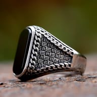 Detail of the intricate woven and chain-link texture on the band of the men's ring.