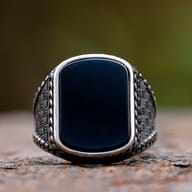 Angled shot of the punk-style men's ring with a prominent, polished black stone.