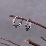 Both octopus tentacle huggie earrings displayed flat on a wooden surface