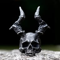 Detailed front view of a 316L stainless steel gothic skull ring with prominent horns on a textured surface