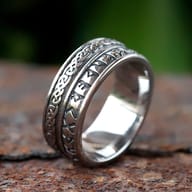 Detailed view of the Celtic knot pattern on the left side of the stainless steel ring band, highlighted against a soft green background.
