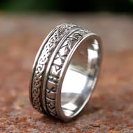 Side profile of the wide stainless steel ring, emphasizing its intricate patterns and the clean separation between design elements.