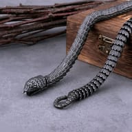 Top-down view of coiled gothic snake bone chain on dark surface