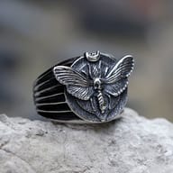 Men's 316L stainless steel ring with detailed Death's Head Moth design on a rock surface.