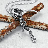 Detail shot of the scythe blade of the stainless steel gothic pendant, with 'DEATH SCYTHE' text partially visible.