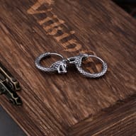 Pair of men's Viking wolf earrings displayed on a dark rustic surface