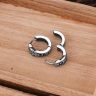 Detailed close-up of the engraved Norse runes and wolf motif on a huggie hoop earring