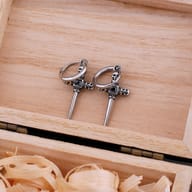 Close-up of gothic cross dagger earring showing skull details and square black zircon center