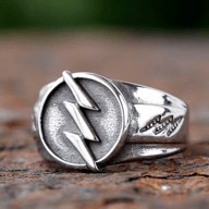 Silver-toned stainless steel ring with a polished lightning bolt on a textured circular face and smaller lightning bolt patterns on the band.