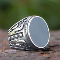 Side angle showing intricate carved patterns on the band of the men's ring.