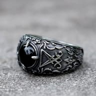 Close-up of the black cabochon stone centerpiece on the 316L stainless steel ring, showing its polished surface and the detailed claw setting surrounded by gothic engravings.