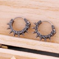 Angled view of antique finish gothic skull huggie earrings resting together