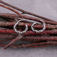 Close-up detail of vintage finish barbed wire huggie hoop earrings