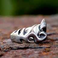 Partial close-up of the right side of the flame-inspired stainless steel ring, highlighting the engraved pattern on its upper edge.