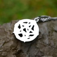 Angled shot of the gothic-inspired stainless steel pentagram pendant, showing intricate snake detail