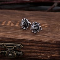 Close-up detail of the antiqued skull and cross design on stainless steel stud earrings