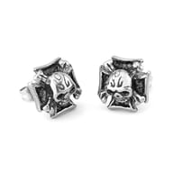Pair of gothic skull cross stud earrings displayed on a dark rustic surface