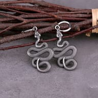 Stainless steel coiled snake hoop earrings resting on wood shavings and timber