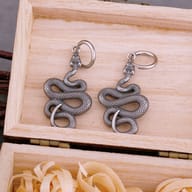 Pair of stainless steel coiled snake drop hoop earrings inside a wooden gift box