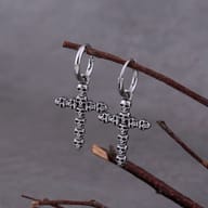Close-up detail of stacked skull cross pendant hanging from steel huggie hoop
