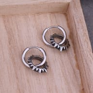 Close-up of the spiked circle charm hanging from a polished stainless steel hoop