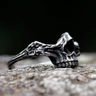 Oblique view of the durable steel skull ring, with a blurred dark background.