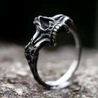 Vintage style skull ring made of steel, resting on a rustic outdoor surface.