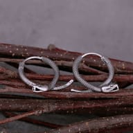 Lifestyle view showing the stainless steel snake hoop earrings worn on an earlobe