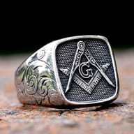 Close-up detail of the compass, square, and 'G' emblem on the ring.