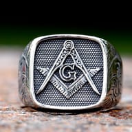 Angled shot of 316L stainless steel Masonic ring on a textured surface.