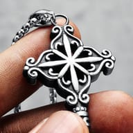 Close-up of a finger holding the shaft of the ornate 316L stainless steel key pendant