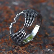 Detailed close-up of the right skeletal hand design on the 316L stainless steel heart ring, showing textured bone details and the ring's band.