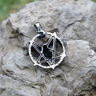 Side profile of the stainless steel pentagram pendant, showing its dimensional design against a blurred natural background
