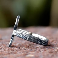Detailed view of the hammered texture on the upper curve of the stainless steel Troll Cross ring.