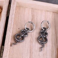 Stainless steel snake drop hoop earrings held to show scale and proportion