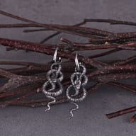 Flat lay view of the pair of punk coiled snake earrings on a textured background