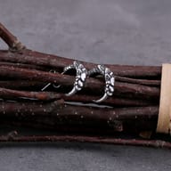 Side angle view of vintage eagle claw stud earring on dark wood background