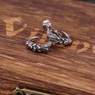 Pair of vintage stainless steel eagle claw stud earrings resting on a rustic wooden box