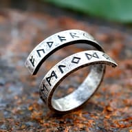 Close-up of the 316L stainless steel Viking rune ring, showing etched Elder Futhark runes on a rustic surface.