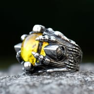 Stylish men's punk rock skull ring with vibrant red stone modeled on a finger for scale and fit.
